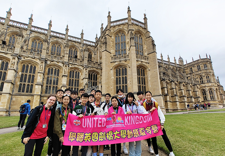 同學在英國劍橋大學哥德式建築前留影,手持夏令營橫額,背景是宏偉典雅的校園建築,感受百年名校氛圍 | 英國遊學團