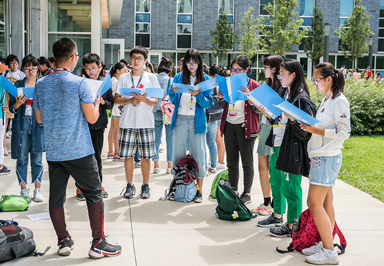 同學於加拿大大學校園中進行戶外學習活動，專注朗讀教材，展現沉浸式學術體驗的真實一刻 | 加拿大遊學團